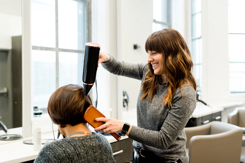 Imagem ilustrativa de uma profissional finalizando um cabelo com escova