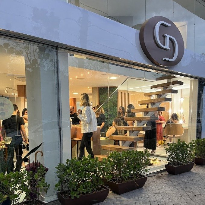 Fachada envidraçada do GD, com a equipe no interior e o letreiro do salão